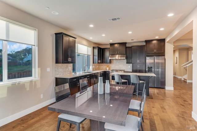 2228 Chateau Ct, Santa Rosa, CA 95404 - kitchen featuring appliances with stainless steel finishes, a center island, light countertops, under cabinet range hood, and backsplash