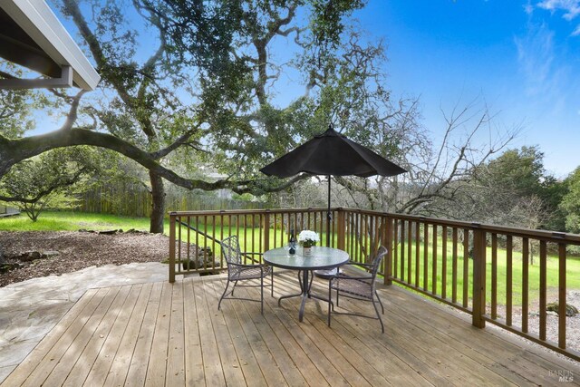 wooden deck with a lawn and outdoor dining area