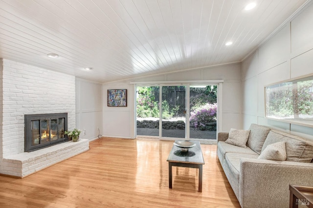living area featuring recessed lighting, vaulted ceiling, ornamental molding, light wood-style floors, and a fireplace
