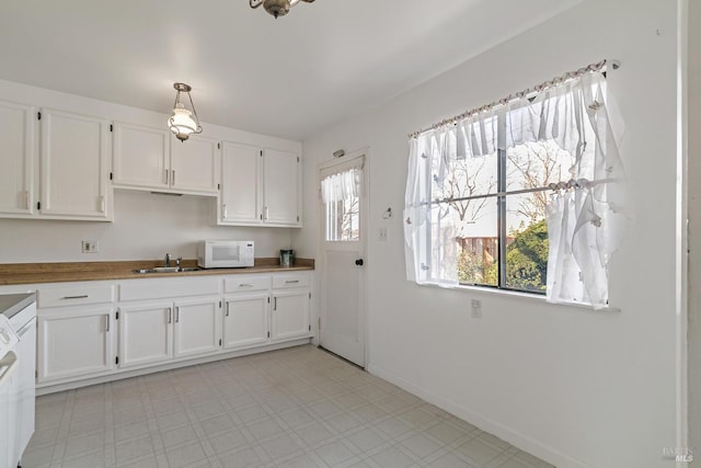 kitchen with sink, white cabinets, butcher block countertops, and decorative light fixtures