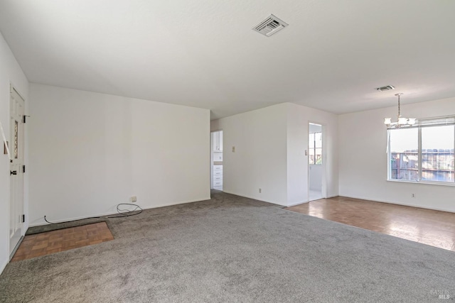 carpeted spare room featuring a notable chandelier