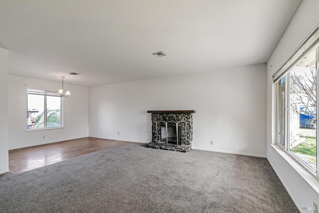 unfurnished living room featuring a fireplace, dark colored carpet, and an inviting chandelier