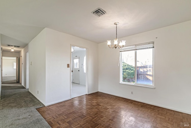 spare room with a notable chandelier and dark parquet floors