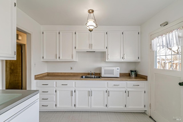 kitchen with decorative light fixtures, sink, and white cabinets