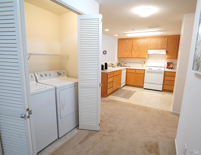 laundry area featuring separate washer and dryer, sink, and light carpet