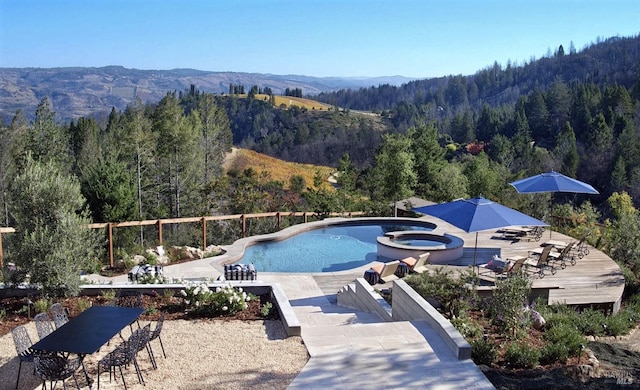 view of pool with a mountain view, a patio area, exterior bar, and an in ground hot tub