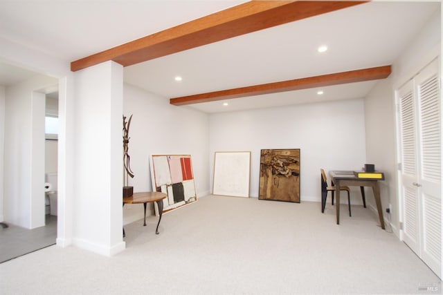 living area with beamed ceiling and light carpet