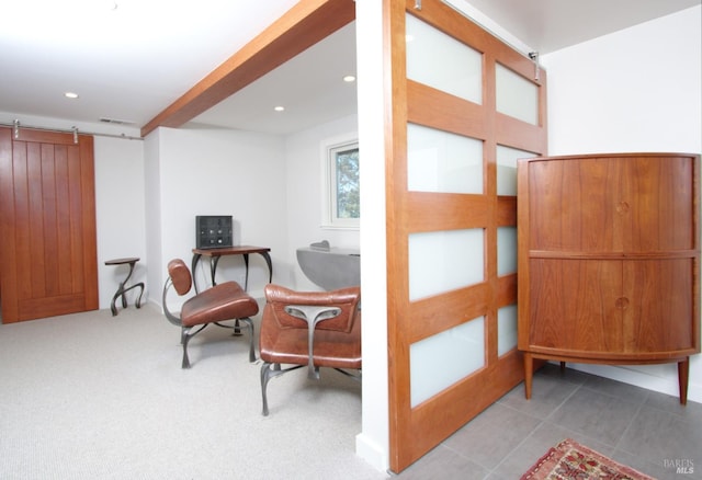 living area featuring a barn door and light colored carpet