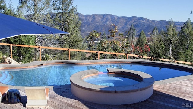 view of swimming pool with an in ground hot tub and a deck with mountain view