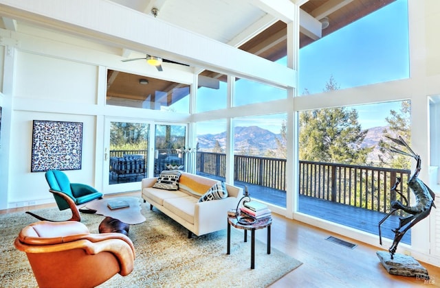 sunroom / solarium with ceiling fan, beam ceiling, and a mountain view