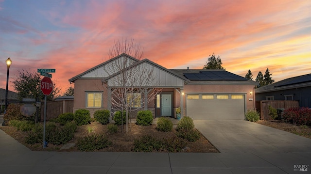 craftsman-style home with a garage, solar panels, fence, concrete driveway, and stucco siding