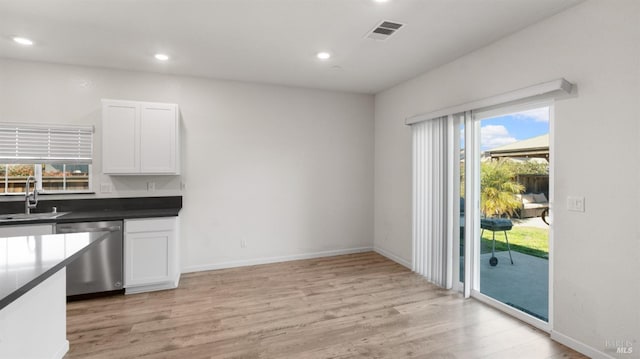 kitchen featuring visible vents, stainless steel dishwasher, white cabinetry, a sink, and light wood-type flooring