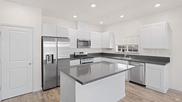 kitchen featuring white cabinets, dark countertops, light wood-style flooring, appliances with stainless steel finishes, and a sink