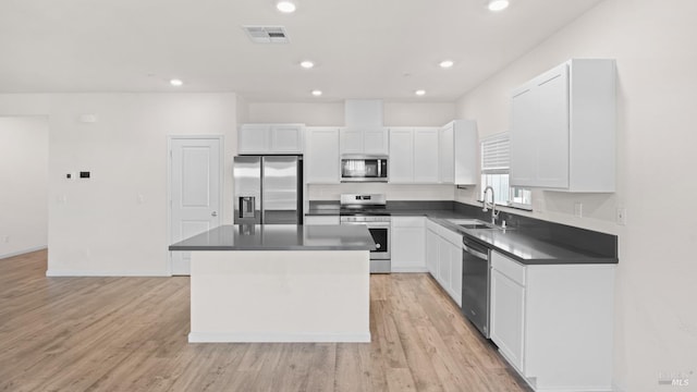 kitchen with visible vents, dark countertops, a kitchen island, stainless steel appliances, and a sink