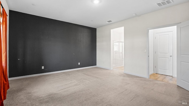 unfurnished room with baseboards, light carpet, and visible vents