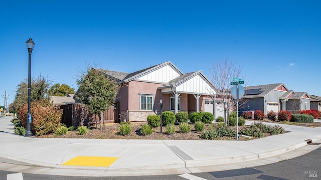 craftsman-style home with a garage, stucco siding, stone siding, and fence