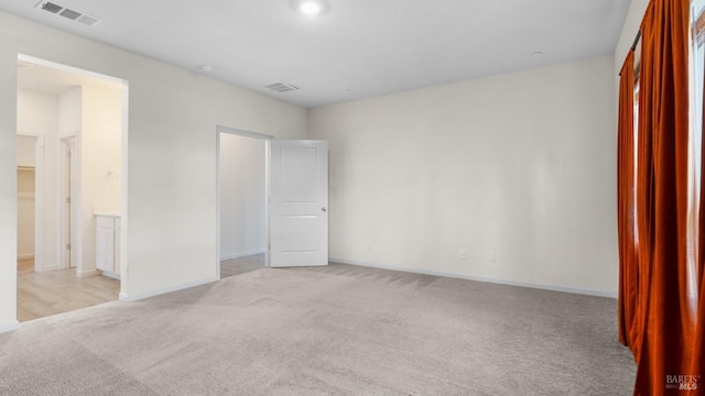 unfurnished bedroom featuring baseboards, light colored carpet, and visible vents