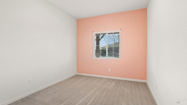 unfurnished room with baseboards and light colored carpet