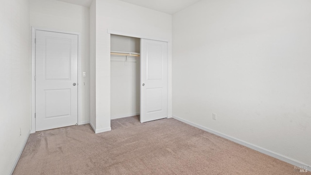 unfurnished bedroom featuring a closet, carpet, and baseboards