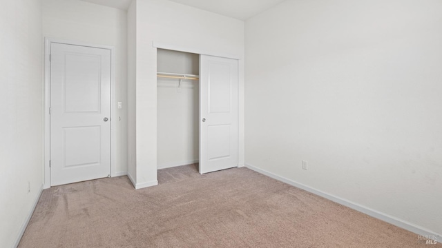 unfurnished bedroom featuring baseboards, carpet, and a closet