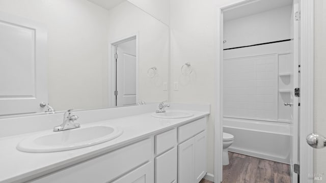 full bath featuring double vanity, wood finished floors, a sink, and toilet