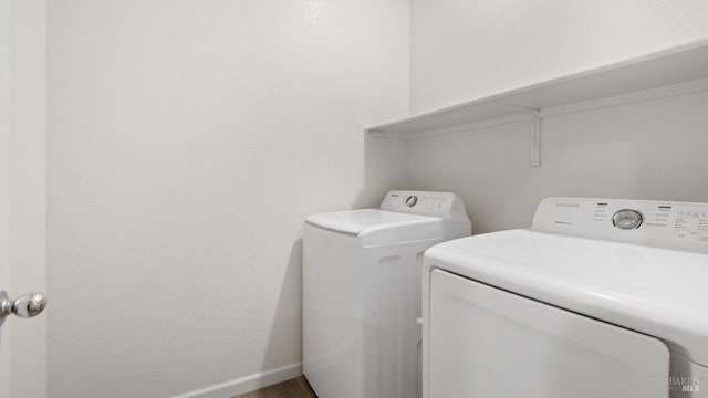 clothes washing area featuring baseboards, laundry area, wood finished floors, and washer and dryer