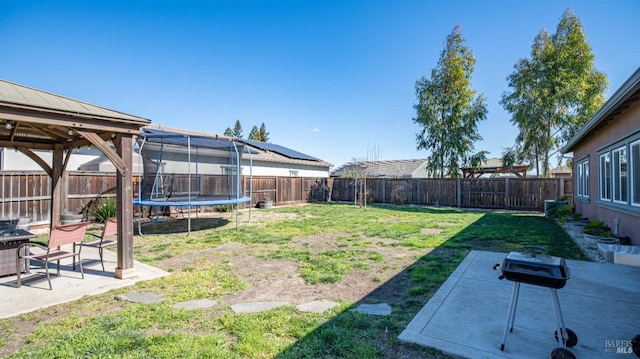 view of yard with a trampoline, a patio area, a fenced backyard, and a gazebo