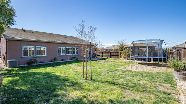 view of yard with a fenced backyard, a trampoline, and central AC