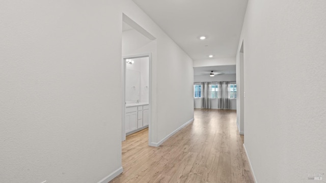 corridor featuring recessed lighting, light wood-style flooring, and baseboards