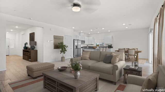 living room featuring recessed lighting, light wood finished floors, ceiling fan, and baseboards