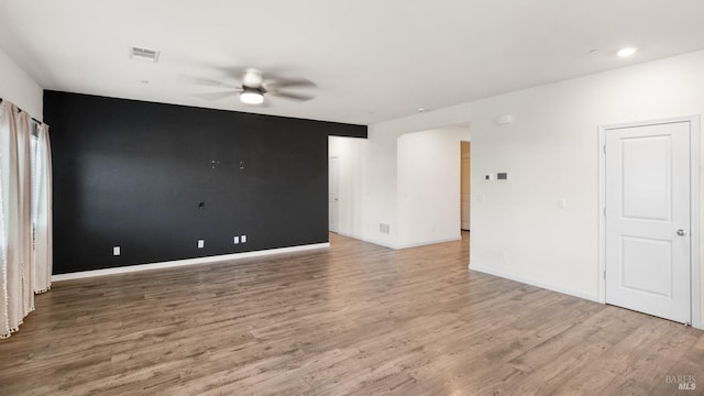 spare room with ceiling fan, light wood-style flooring, visible vents, and baseboards