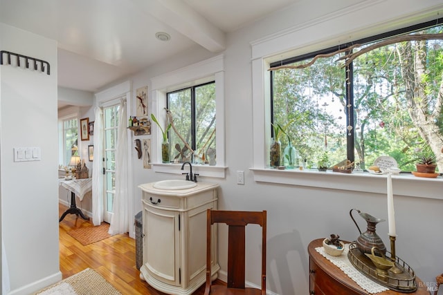 bathroom with wood-type flooring, sink, and beam ceiling