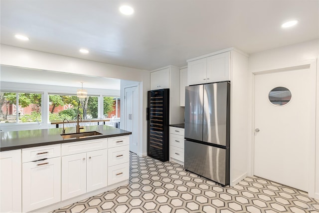 kitchen featuring beverage cooler, a sink, white cabinets, freestanding refrigerator, and dark countertops