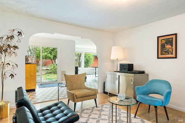 living area featuring light wood finished floors, baseboards, and arched walkways