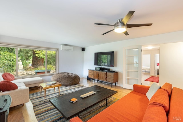 living room with light wood-style floors, ceiling fan, and a wall mounted air conditioner