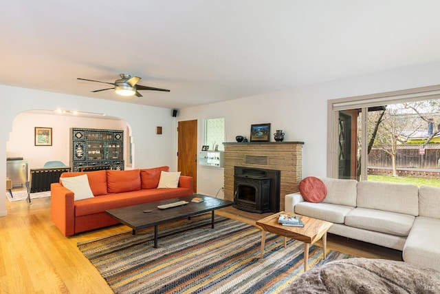 living area featuring arched walkways, ceiling fan, and light wood-type flooring