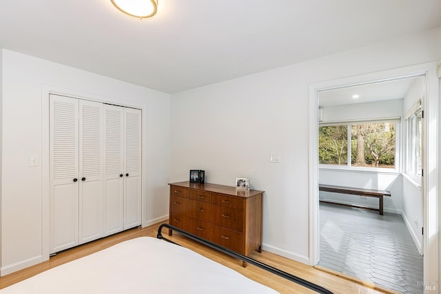 bedroom with a closet, baseboards, and light wood finished floors