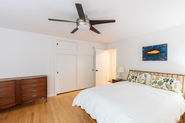 bedroom with light wood-type flooring, ceiling fan, and a closet