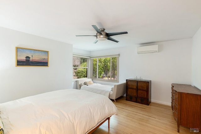 bedroom with light wood finished floors, baseboards, a ceiling fan, and a wall mounted AC