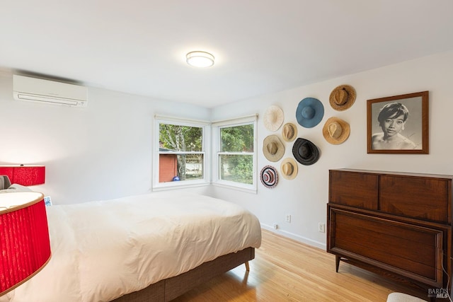 bedroom with baseboards, an AC wall unit, and wood finished floors