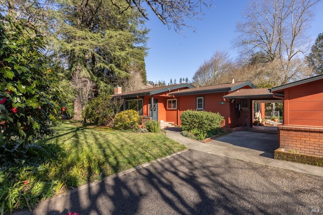 ranch-style home with a carport, a front lawn, and driveway