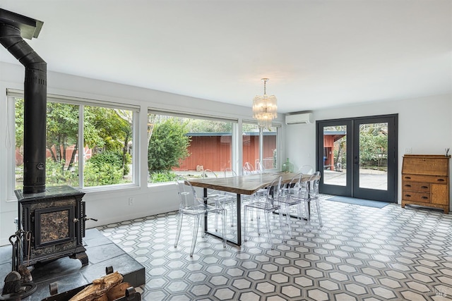 dining room featuring a wood stove, an inviting chandelier, french doors, and a wall mounted AC