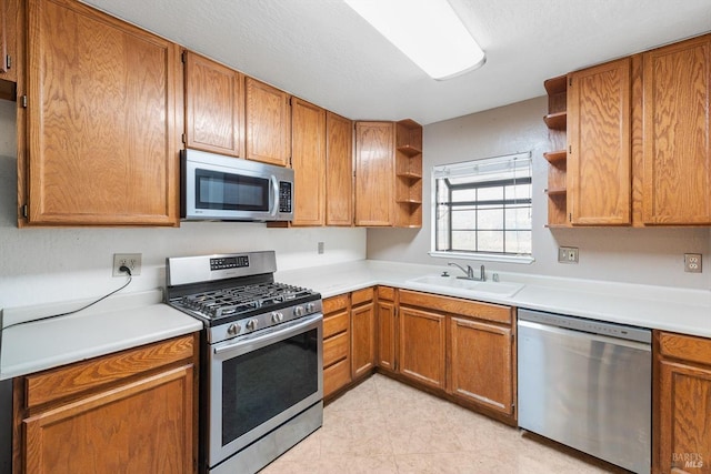 kitchen with appliances with stainless steel finishes, sink, and a textured ceiling