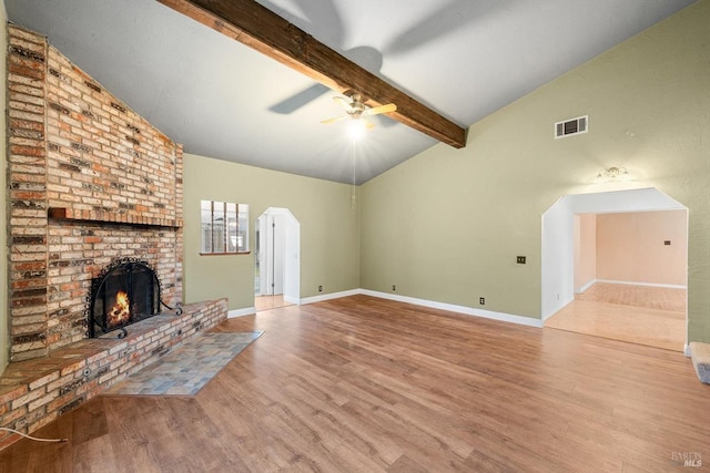 unfurnished living room featuring ceiling fan, lofted ceiling with beams, a brick fireplace, and light hardwood / wood-style flooring