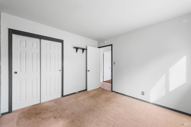 unfurnished bedroom with light carpet and a closet