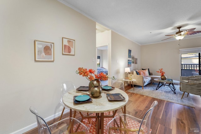 dining space featuring a ceiling fan, baseboards, wood finished floors, and ornamental molding