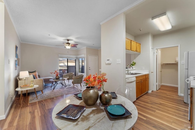 dining area with baseboards, light wood finished floors, a ceiling fan, and crown molding