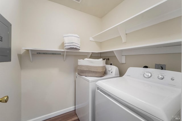 laundry room with laundry area, wood finished floors, baseboards, independent washer and dryer, and electric panel