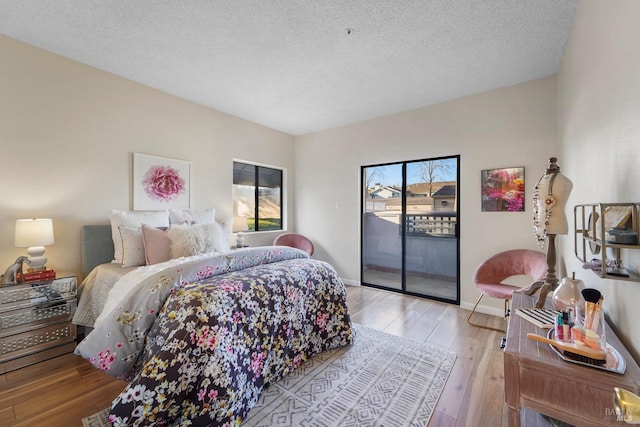 bedroom with access to outside, baseboards, wood-type flooring, and a textured ceiling