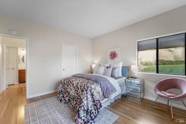 bedroom with wood-type flooring, a textured ceiling, and baseboards